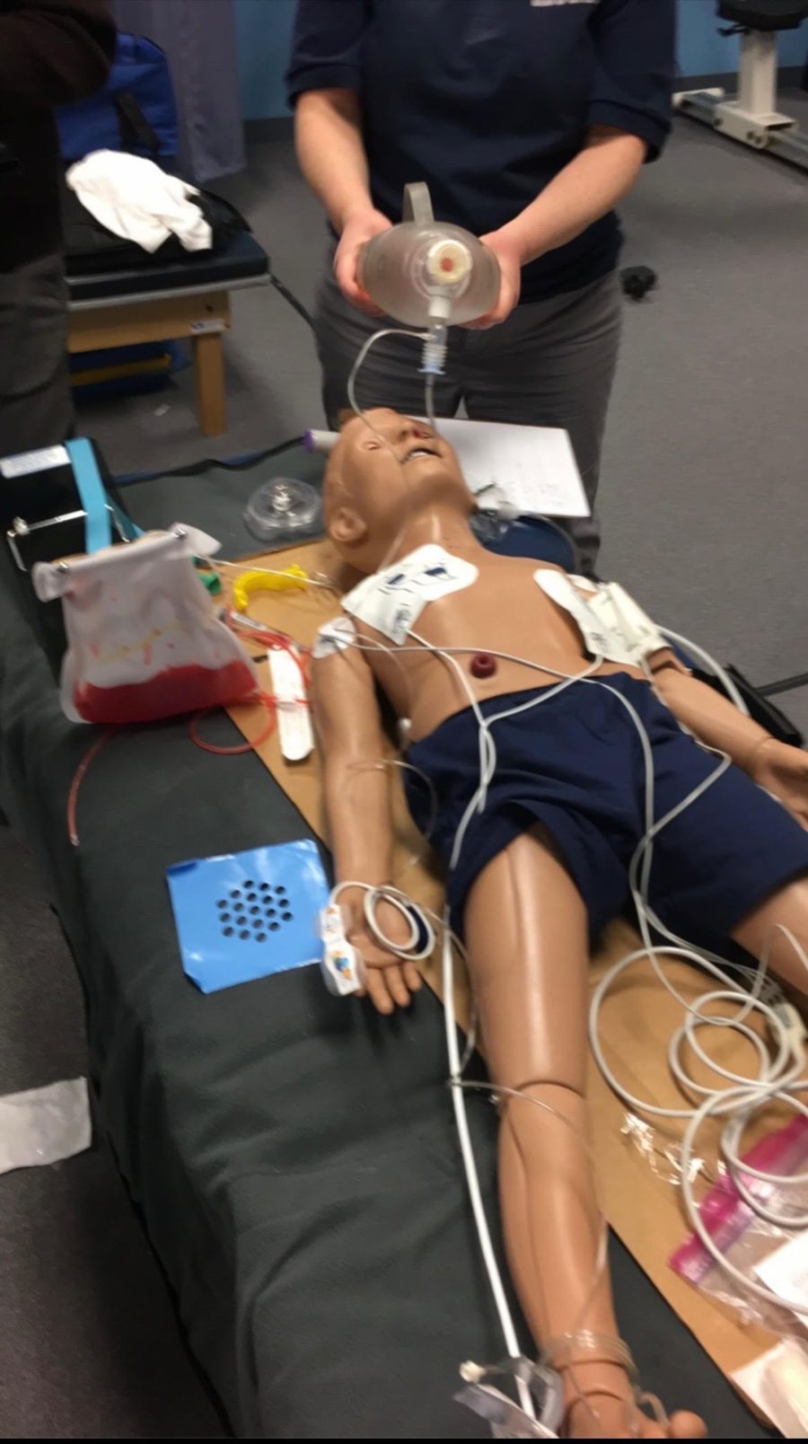 ACLS training scenario with manikin, bag-valve-mask ventilation, AED pads and IV access